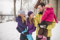 Mother and father carrying daughters in snow — Stock Photo