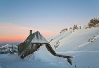 Nieve apilada por casa en la ladera - foto de stock