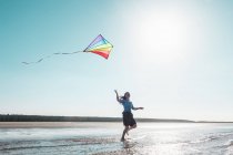 Donna aquilone volante sulla spiaggia — Foto stock