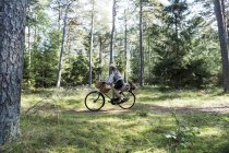 Зріла жінка катається на велосипеді з кустарними кошиками в лісі — стокове фото