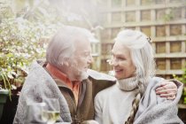 Старша пара, загорнута в ковдру в саду — стокове фото