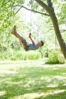 Boy swinging from tree outdoors — Stock Photo