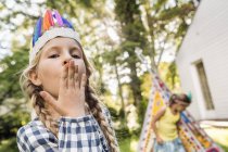 Portrait of girl in native American headdress with hand over mouth — Stock Photo