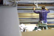 Mann durchsucht Lagerregale in Bilderrahmenwerkstatt — Stockfoto