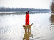 Молодая женщина в реке с собакой в рябь — стоковое фото