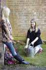 Дві дівчини в саду поливають клумбу — стокове фото