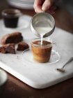 Immagine ritagliata della donna versando il latte nella tazza di caffè — Foto stock