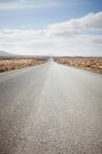 Paved road in rural landscape under cloudy sky — Stock Photo