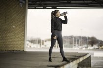 Läuferin trinkt Mineralwasser auf Lagerplattform — Stockfoto