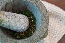 Herbs pounding in stone bowl, close up shot — Stock Photo