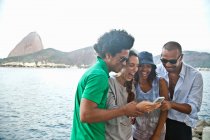 Four friends looking at smartphone, Rio de Janeiro, Brazil — Stock Photo