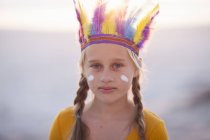 Retrato de menina vestida como nativa americana com penas cobertura para a cabeça — Fotografia de Stock