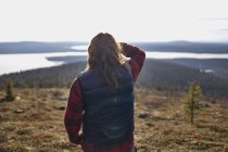 Rear view of hiker looking out to lake, Keimiotunturi, Lapland, Finland — Stock Photo