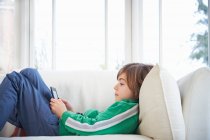 Мальчик на диване с цифровым планшетом — стоковое фото