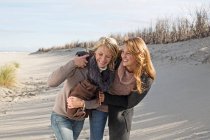 Donne sorridenti che camminano sulla spiaggia — Foto stock