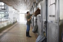 Male stablehand petting horse in stables — Stock Photo