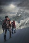 Zwei bergsteiger auf einem schneebedeckten hang beobachten die grand jorasses, im mont blanc massiv, chamonix, franz — Stockfoto