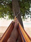 Männliche Füße liegen in Hängematte am Strand — Stockfoto