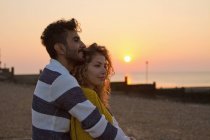 Jovem casal na praia ao pôr do sol — Fotografia de Stock