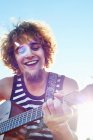 Jovem tocando guitarra ao sol — Fotografia de Stock