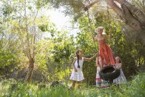 Чотири дівчини грають на дереві шини гойдаються в саду — стокове фото