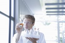 Male scientist analyzing erlenmeyer flask in lab — Stock Photo