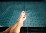 Woman with feet in swimming pool — Stock Photo