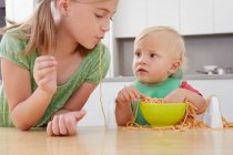 Niña y niño jugando con espaguetis - foto de stock