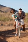 Couple riding bicycle on dirt road — Stock Photo