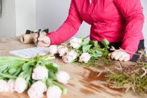Жінка розставляє троянди у флористах — стокове фото
