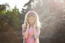 Дівчина-підліток в навушниках на сонячному світлі — стокове фото