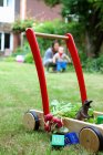 Mãe e criança com carrinho de empurrar e brinquedos no jardim — Fotografia de Stock
