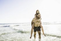 Mann in Badehosen gibt Freundin huckepack im Meer, Kapstadt, Südafrika — Stockfoto