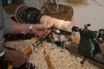 Hombre mayor moldeando pieza de madera con herramientas de carpintería, enfoque en las manos - foto de stock