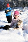 Enfants et chien ramassant du bois dans la neige — Photo de stock