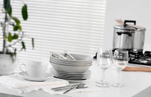 Stacked dishes and cutlery on table — Stock Photo