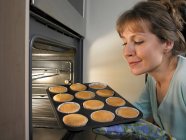 Mujer hornear cupcakes en la cocina - foto de stock