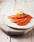 Ломтики копченого лосося с черным перцем, укропом и лимоном — стоковое фото
