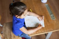 Young girl drawing picture on desk — Stock Photo