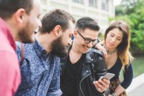 Group of friends looking at message on cellphone together — Stock Photo