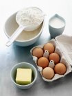 Farina, uova, latte e burro sul tavolo della cucina — Foto stock