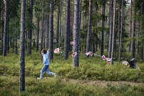 Boy running through forest pulling bunting — Stock Photo