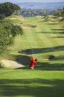 Vista de ángulo alto del campo de golf y golfista tomando swing de golf - foto de stock