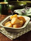 Golden roast potatoes in vintage dish, wooden table — Stock Photo
