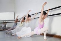 Ballet dancers posing at barre — Stock Photo