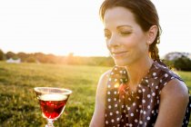 Зріла жінка споглядає червоне вино в парку — стокове фото