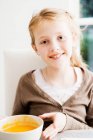 Menina sorridente segurando tigela de sopa — Fotografia de Stock