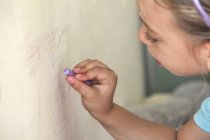Маленькая девочка рисует на стене мелом — стоковое фото