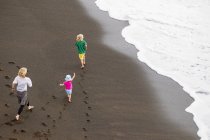 Madre e hijos caminando en la playa - foto de stock