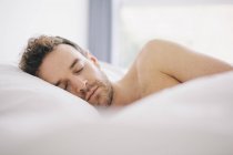 Junger Mann liegt auf der Seite schlafend im Bett — Stockfoto